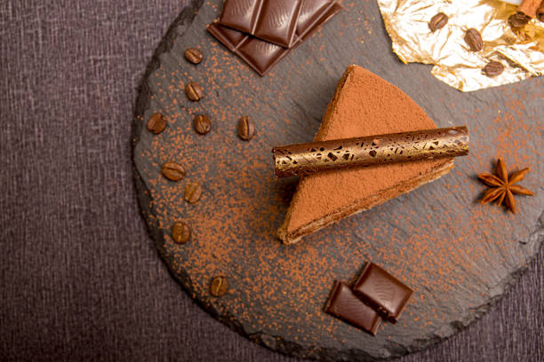 Piece of tiramisu cake on black slate garnish with mint and chocolate. Italian traditional dessert. White background. Top view