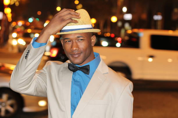 confident african man holding hat while walking - high society men tuxedo party imagens e fotografias de stock