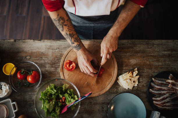 chef utiliza el cuchillo para tomate rebanada en pedazos más pequeños para la ensalada - vegetable cutter fotografías e imágenes de stock