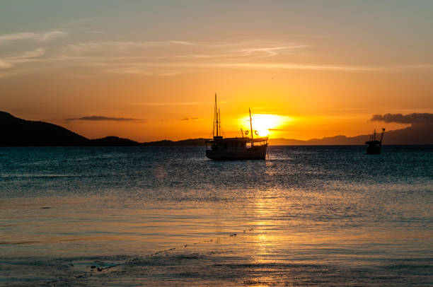 Horizontal view of an old fishing boat shot against gold colored sunset at Caribbean Sea