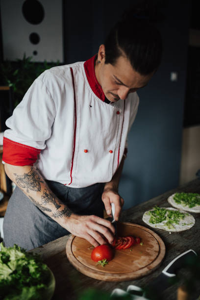 istock Beautiful chef chopping tomato on wooden board 813758308