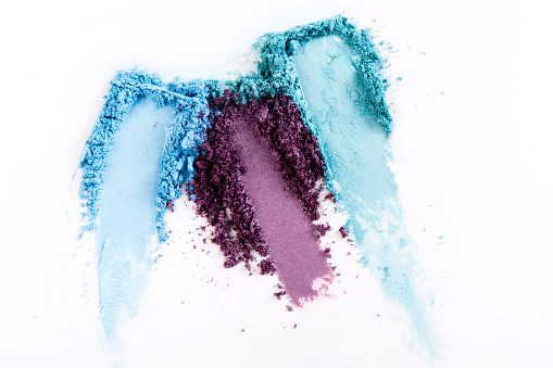 Makeup strokes, cosmetics background. Eyeshadow crushed palette, blue and violet colorful powder on white, art of make-up