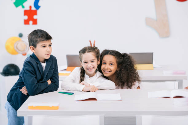 istock Adorable multiethnic schoolkids having fun while sitting at desk in class 813774992