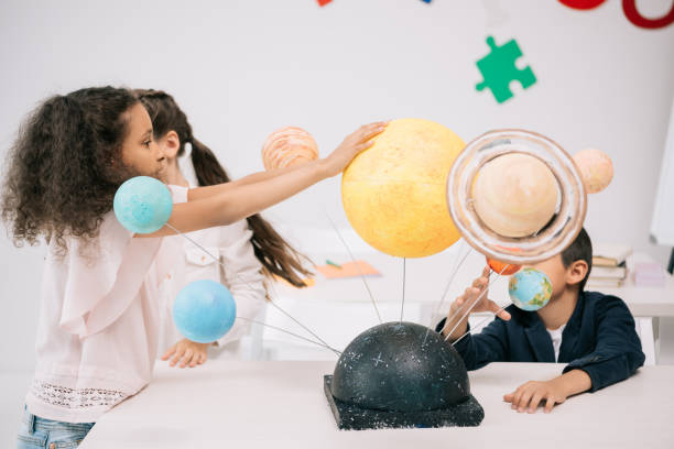 istock Multiethnic group of schoolchildren working with solar system model in classroom 813780560