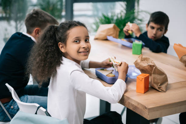 istock Cute multiethnic schoolkids eating lunch while sitting at table 813785686