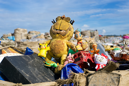 Kota Kinabalu, Malaysia - 09 July, 2017: An abandoned dirty Garfield and other toys at the landfill site in Sabah, Borneo. In Malaysia, the absence  of an integrated waste management system resulted with more than 10.40  million tonnes of municipal solid waste being disposed off into landfills annually.