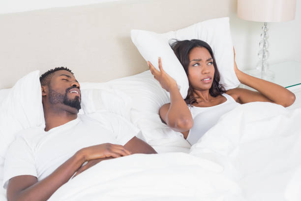 verärgert frau für ihre ohren mit kissen zu blockieren, schnarchen - couple love snoring sleeping stock-fotos und bilder