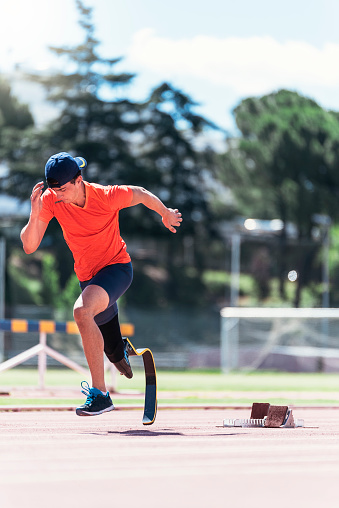 Disabled man athlete training with leg prosthesis. Paralympic Sport Concept.