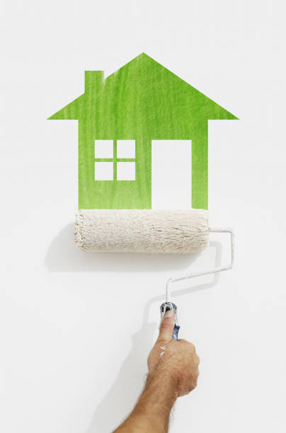 paint roller hand with green house symbol painting on wall isolated on white