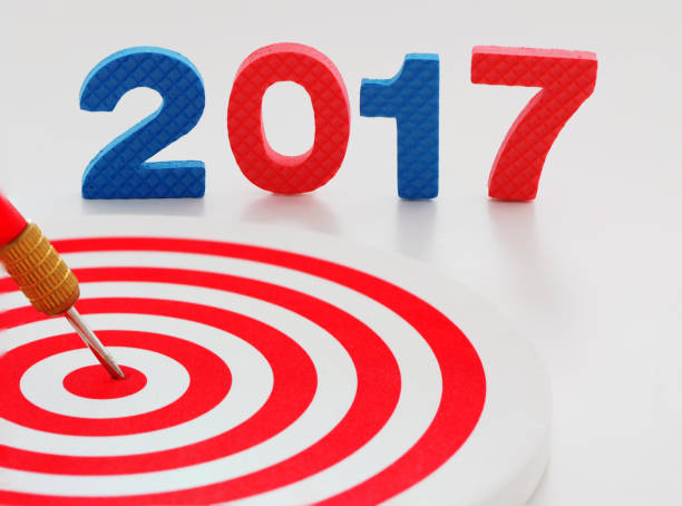 istock Year 2017 goal, two thousand seventeen with red bullseye dart arrow hitting target center dartboard in background. Happy New Year. 813847574