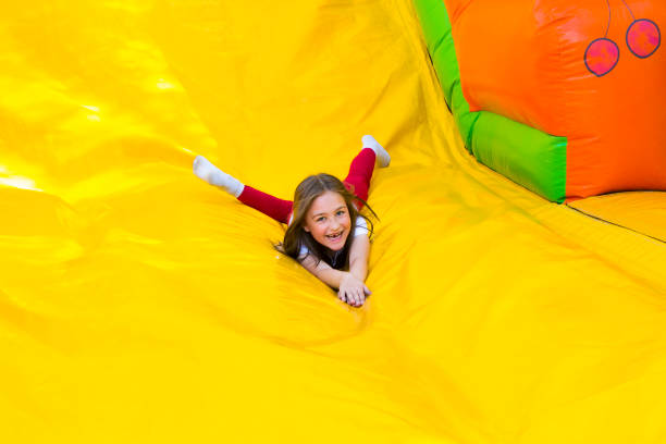 Girl Slide Down Happy little girl having lots of fun on a jumping castle while sliding. bouncing photos stock pictures, royalty-free photos & images