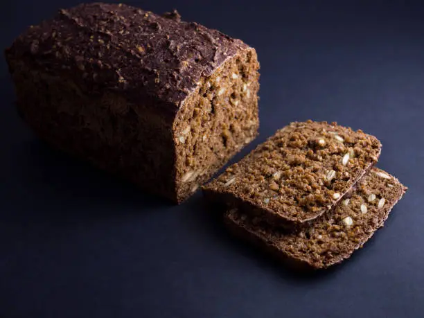 Danish rye bread made from sour dough with whole grain flour and seeds. Sliced and isolated on black background