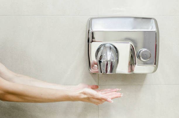 Woman dries her hands Woman dries her hands in the bathroom paper dispenser stock pictures, royalty-free photos & images