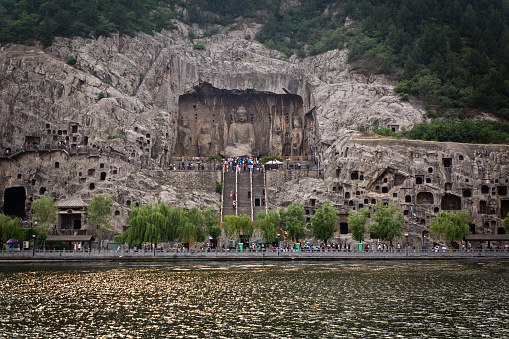 Worshiper, tourists and visitors visiting the Longmen Grottoes in Luoyang, China. The historic Longmen Grottoes, a series of ancient caves carved with numerous buddhist figures. Created between from 493 AD to 1127 AD, the Longmen Grottoes is a famous historic site and a tourist destination in the city of Luoyang, China