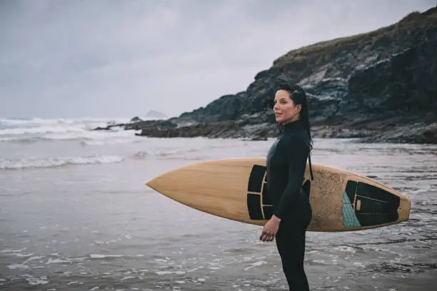 Candid Portrait of Female Surfer, mid 30's on Perranporth Beach, Newquay, Cornwall on a overcast rainy day.