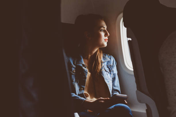 mujer pasajero mirando fuera de la ventana de avión - silla al lado de la ventana fotografías e imágenes de stock