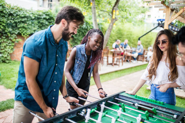istock Multi-ethnic group of friends playing foosball at the pub 813910486