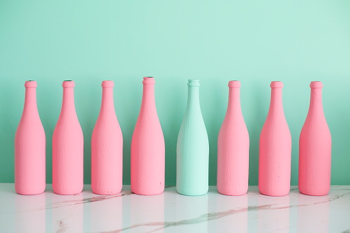 Colorful bottles on the table against pastel colored background.