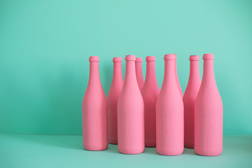 Colorful bottles on the table against pastel colored background.