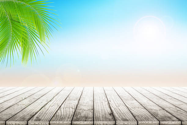 istock Empty wooden table and palm leafs with party on beach background blurred. 813927568