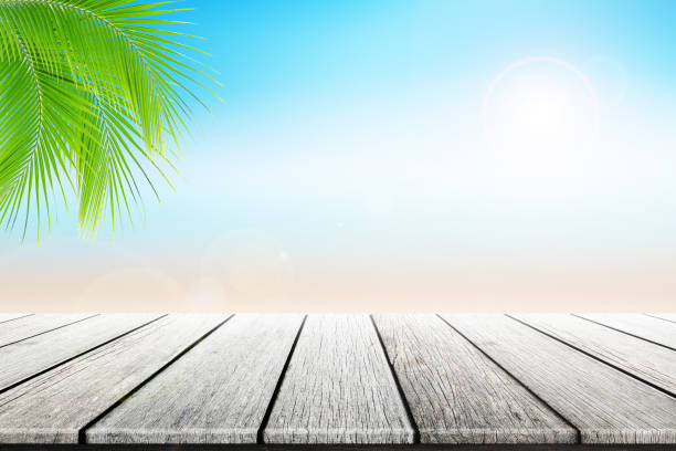 istock Empty wooden table and palm leafs with party on beach background blurred. 813929702