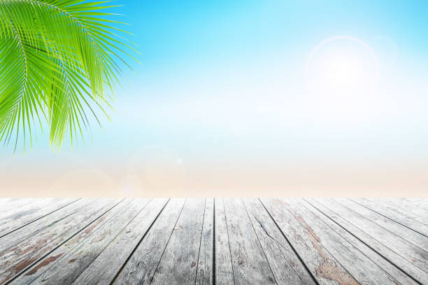 istock Empty wooden table and palm leafs with party on beach background blurred. 813929828