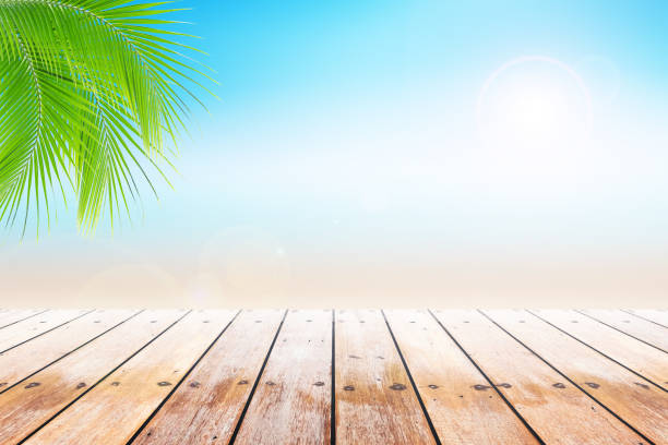 istock Empty wooden table and palm leafs with party on beach background blurred. 813929992