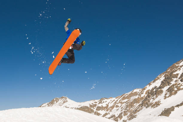 istock Man with snowboard flying in midair against blue sky 813973072