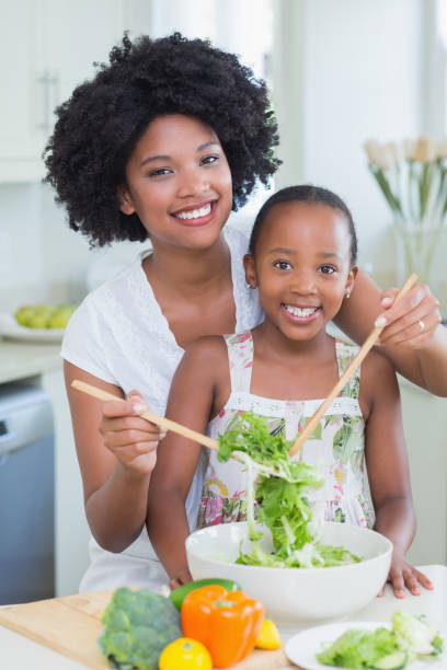 istock Mother and daughter making a salad together 813979842