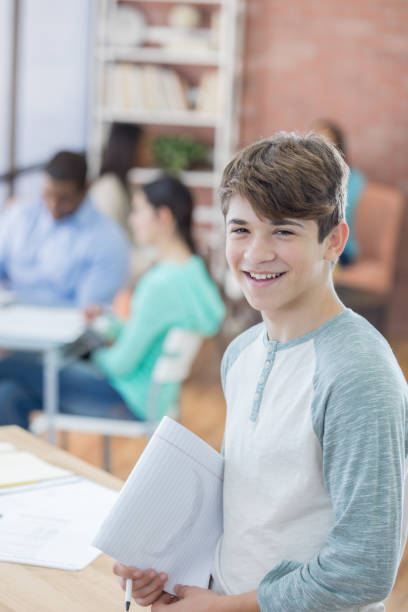 istock Cheerful teenage boy prepares to study in the library 813979988