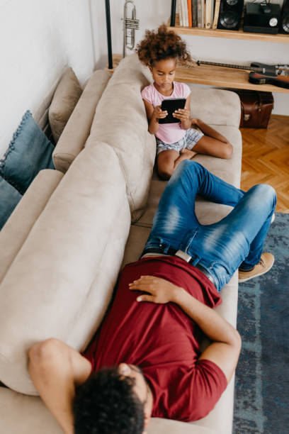 istock Father relaxing after work while his little girl is playing on tablet 813980362