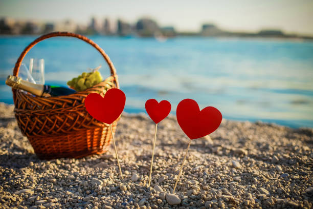 pic-nic. champagne. panier de pique-nique. plage de la mer belle. coeurs sur la plage se tiennent sur des bâtons. saint-valentin - isolated remote plaid nobody photos et images de collection