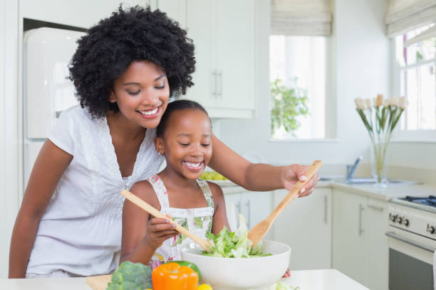 Mother and daughter making a salad together Mother and daughter making a salad together at home in the kitchen throwing photos stock pictures, royalty-free photos & images