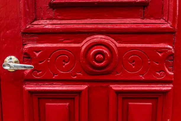 Macro closeup of vibrant red door with handle