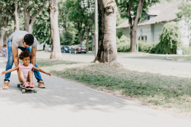 istock Single parent with cute daughter playing in the park with skateboard 814010528