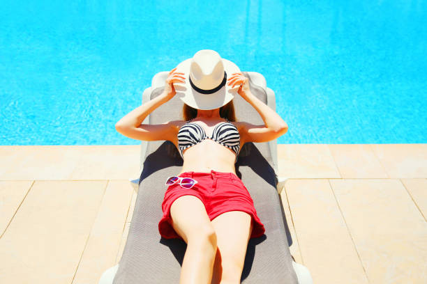 istock Summer holidays - woman lying resting on a deckchair, blue water pool background 814010566