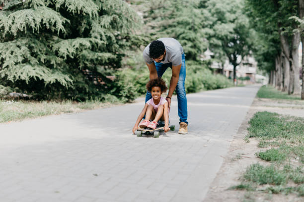 istock Father pushes his daughter who sits on a skateboard 814011142