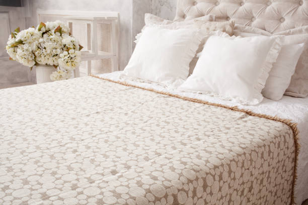 istock Close up white bed with  bedspread and pillows, flowers behind 814023828