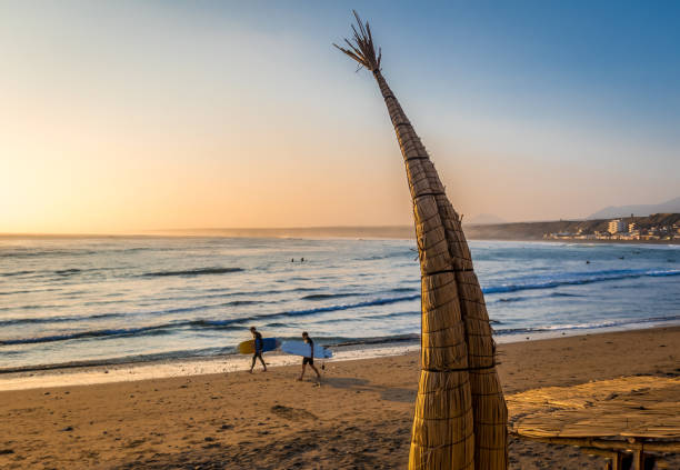 Huanchaco Beach and the traditional reed boats (caballitos de totora) - Trujillo, Peru Trujillo, Peru - May 2016: Huanchaco Beach and the traditional reed boats (caballitos de totora) and surfers - Trujillo, Peru trujillo peru stock pictures, royalty-free photos & images