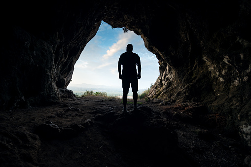 Silhouette of a male person at the cave entrance