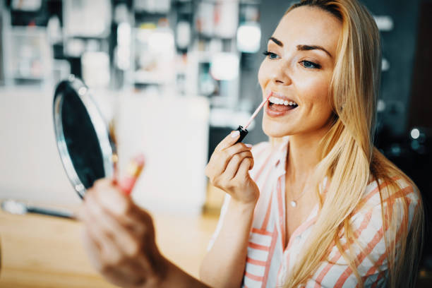 istock Young beautiful woman applying make up using small mirror 814068322