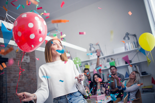 Group of young colleagues celebrating birthday party in modern office, focus on a young woman