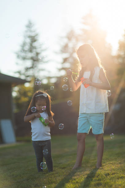 istock Two adorable ethnic girls blow bubbles in the backyard 814077268