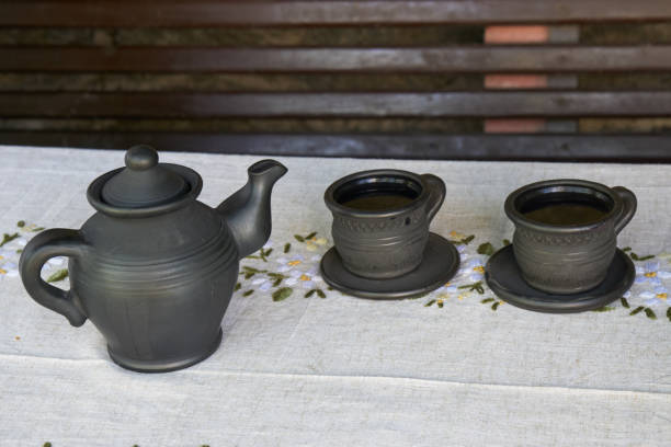 morning tea ceremony. clay teapot and two black cups of tea on the wooden table with grey tablecloth