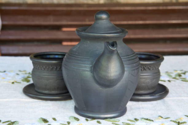 brave ceramic tea kettle with two shy cups behind on a table