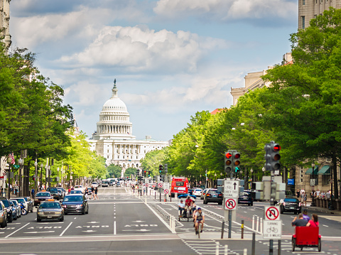 Washington, D.C. USA - May 24, 2014: Late afternoon sun shines straight down Pennsylvania Avenue in Washington, D.C. USA. People and cars are visible with emphasis on Capitol Building. This photograph was taken late afternoon with full frame camera and Zeiss telephoto lens.