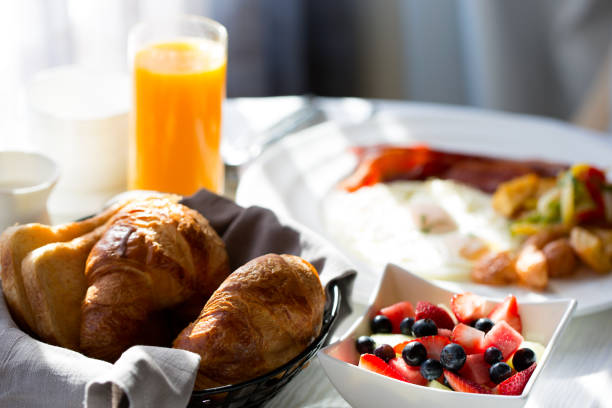 breakfast at hotel delicious healthy fruit bowl for breakfast with orange juice and pastries in the background, in-room dining at the hotel bed breakfast pictures stock pictures, royalty-free photos & images