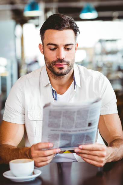 istock Young man having cup of coffee reading newspaper 814118170