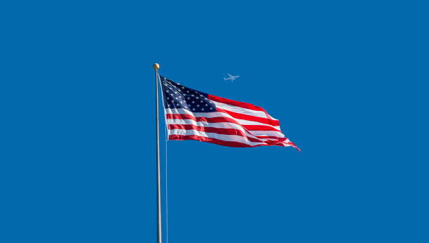 istock Low angle view of waving American flag with moving airplane 814120854