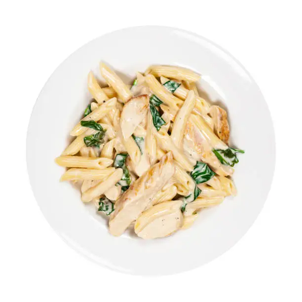 Chicken Alfredo Pasta with Spinach Isolated on White. Selective focus.